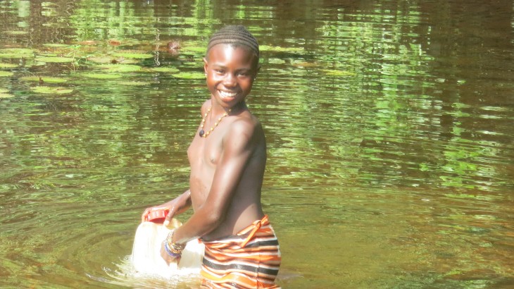 Une jeune fille puise de l’eau dans un bidon au marigot. L'eau provenant du puits récemment remis en état est bien plus propre ! 