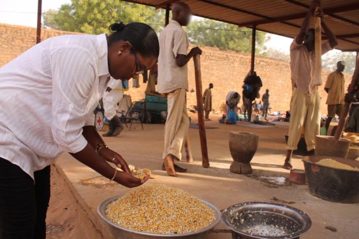 Sikasso prison, Mali. An ICRC delegate works alongside the prisoners to pound corn.